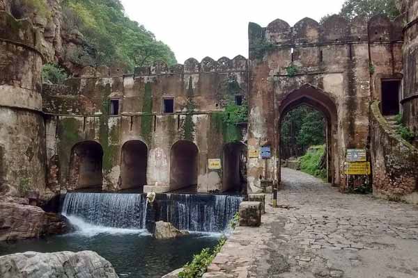 Historic Ranthambhore gateway beside a stone-lined cascade